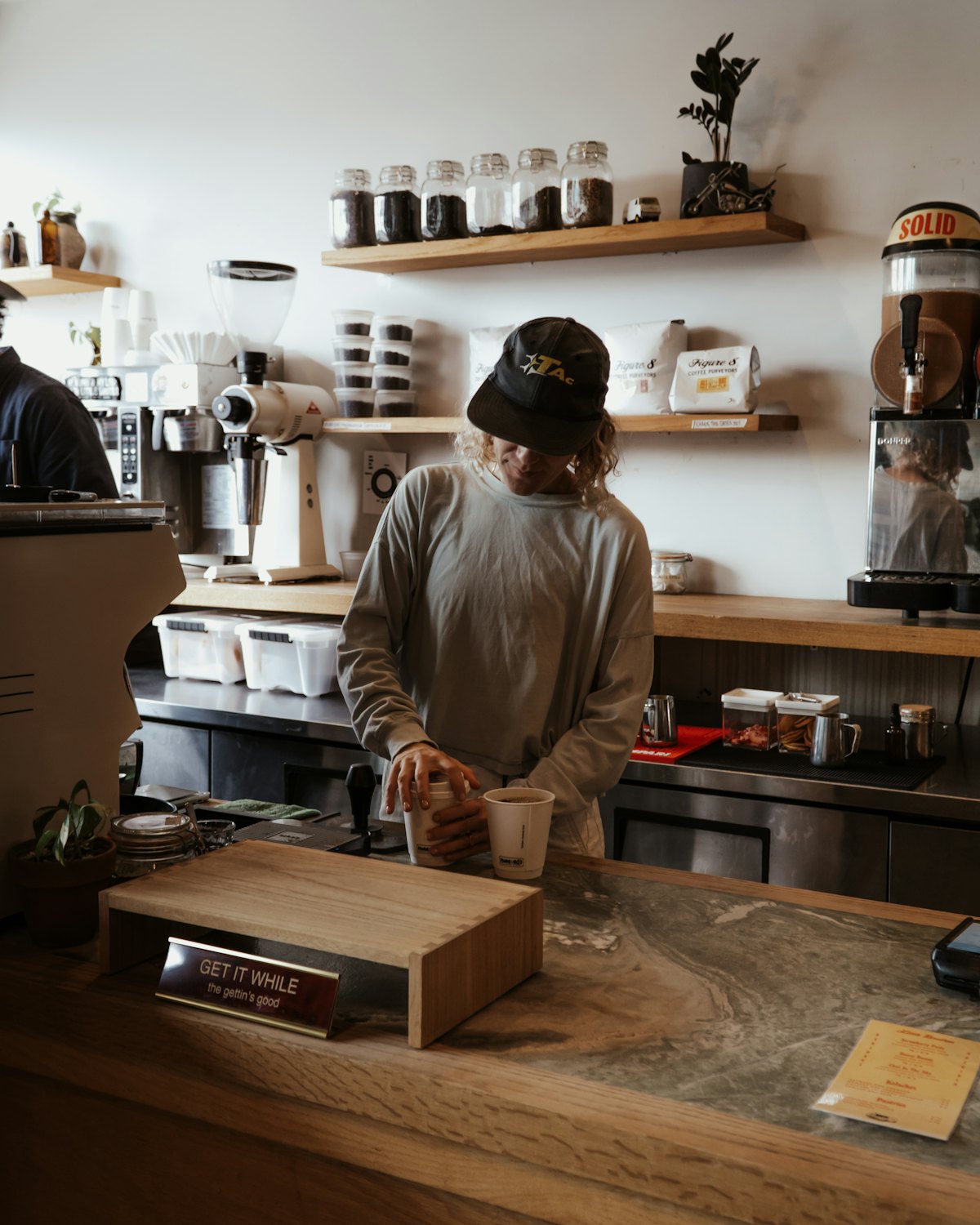 Commerçant derrière le comptoir de bois de son café, penché sur son travail